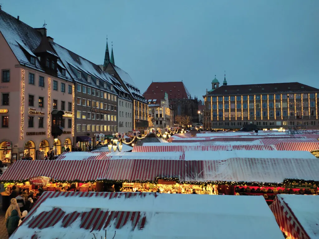 The Christmas market in Nuremberg with a view of the old buildings in the city and a dusting of snow.